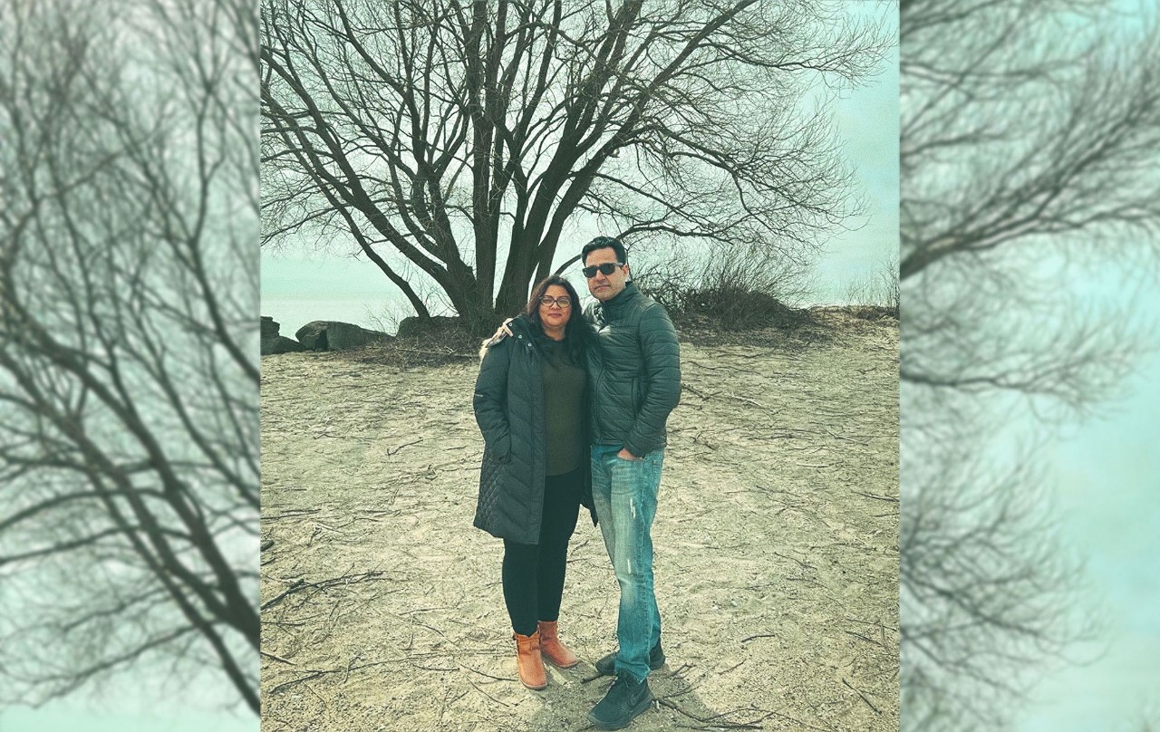 Un couple debout devant un arbre, l'air heureux et détendu.